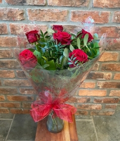 6 long stemmed luxury red roses in a vase.